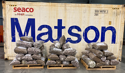 Six tonnes of seized tobacco in front of a shipping container.
